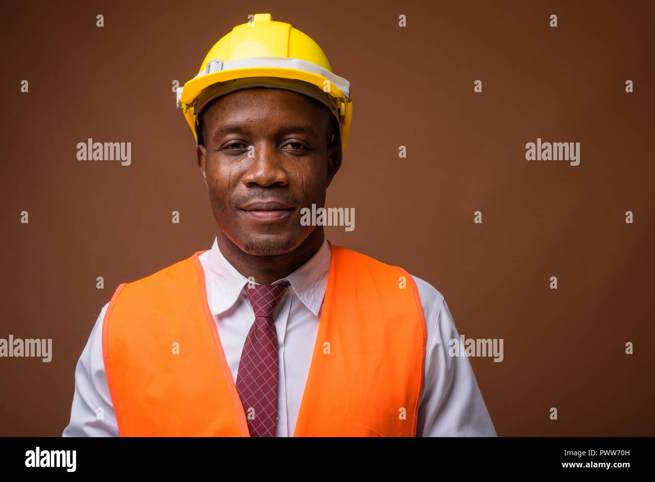 Jeune homme africain construction worker contre fond brun Banque D'Images