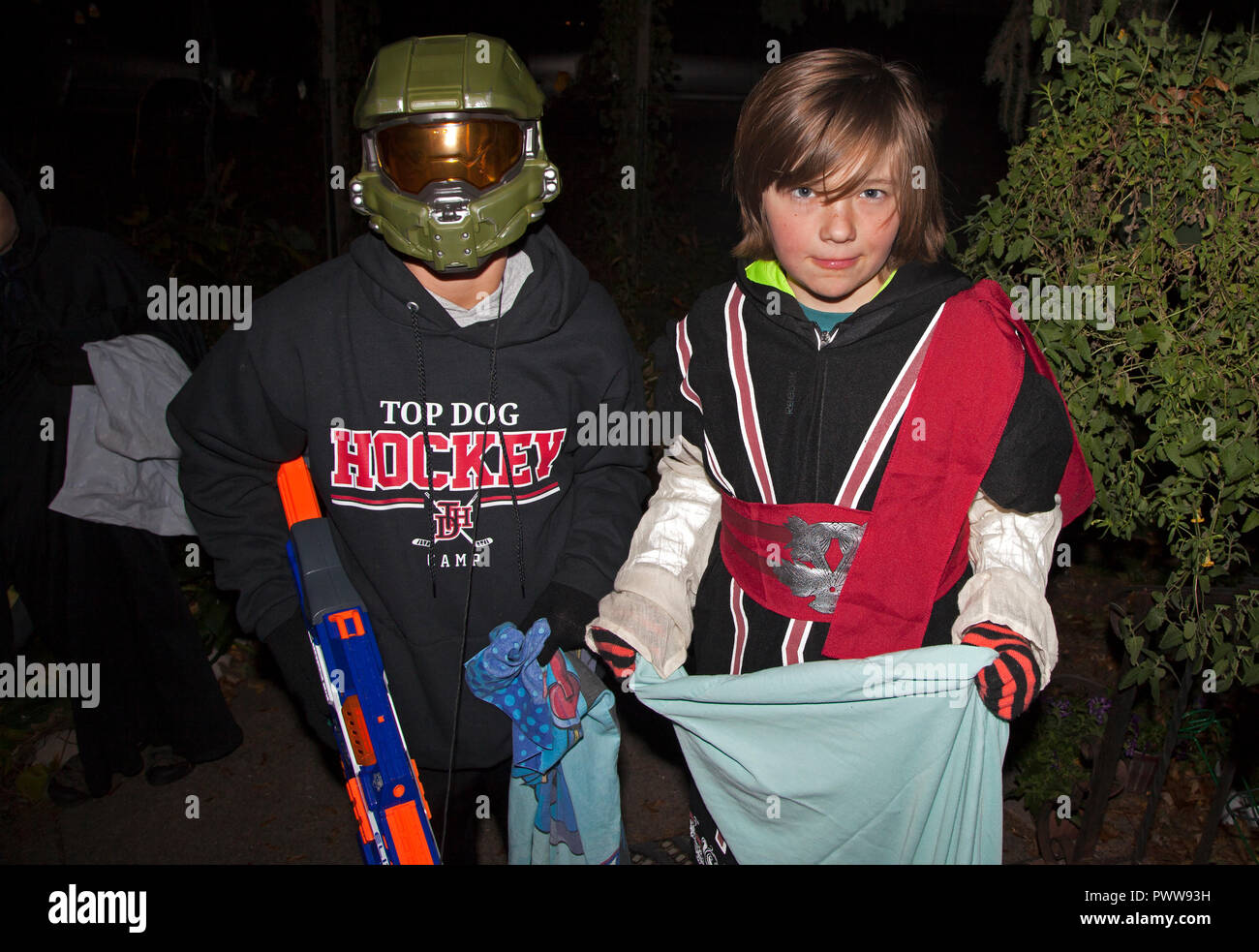 Trucs et astuces d'Halloween ou traite les enfants au hockey et costumes guerrier holding candy sac et pistolet nerf. St Paul Minnesota MN USA Banque D'Images