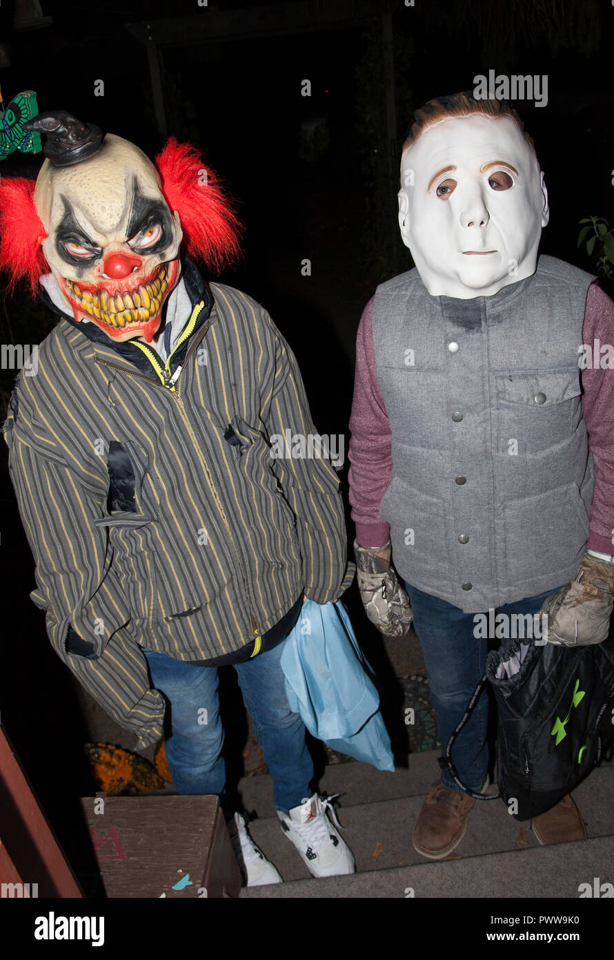 Trucs et astuces Halloween Halloween ou le port de masque clown effrayant du joker et blanc face complice des bonbons pour la collecte des temps difficiles. St Paul Minnesota MN USA Banque D'Images