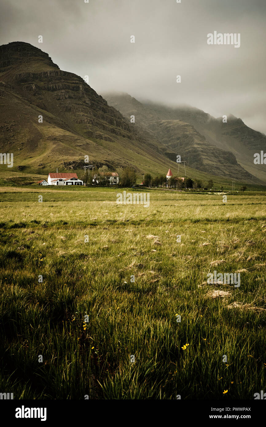 Une ferme et l'église dans la montagne et plaine de paysage sud-est de l'Islande. Banque D'Images