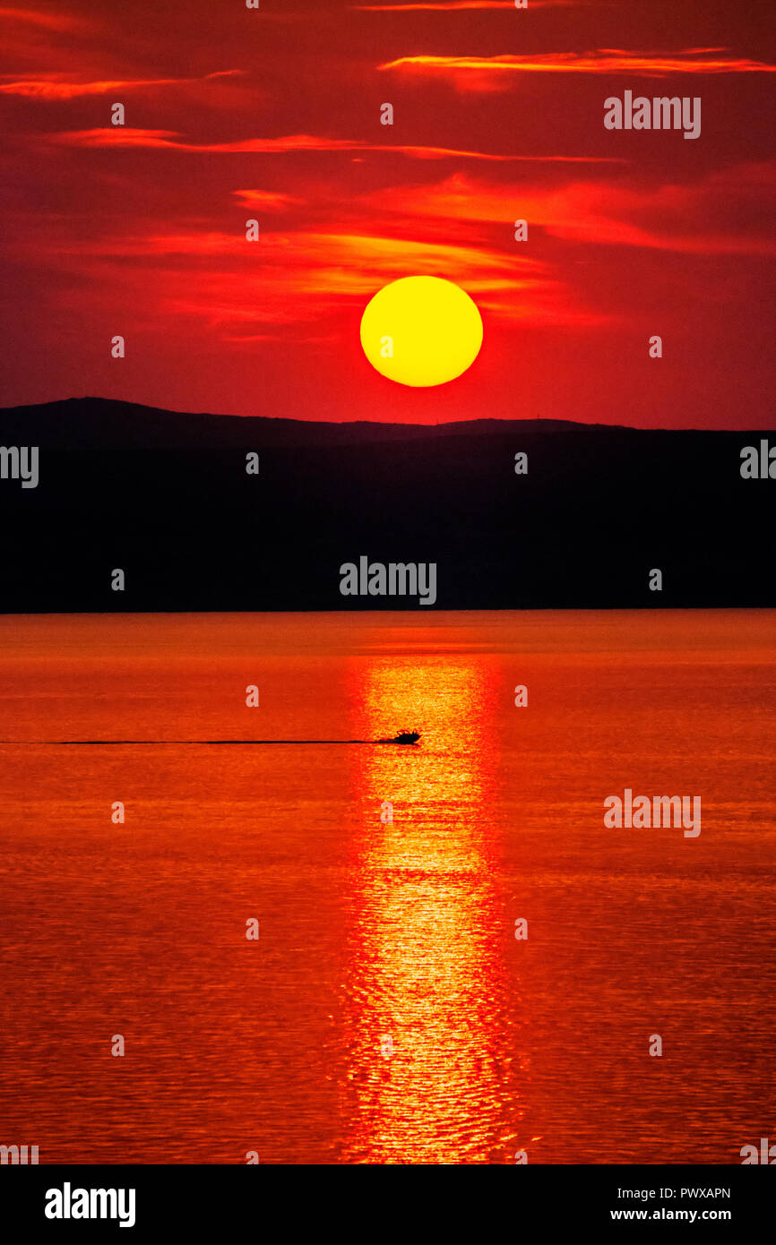 Voile sous un beau coucher de soleil colorés à la mer avec des nuages et le soleil brille. Tourné en Croatie. Banque D'Images