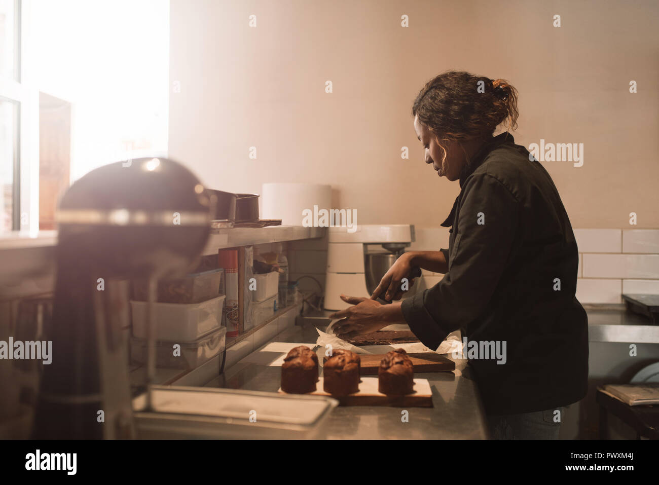 Baker brownies de coupe au comptoir d'une cuisine commerciale Banque D'Images