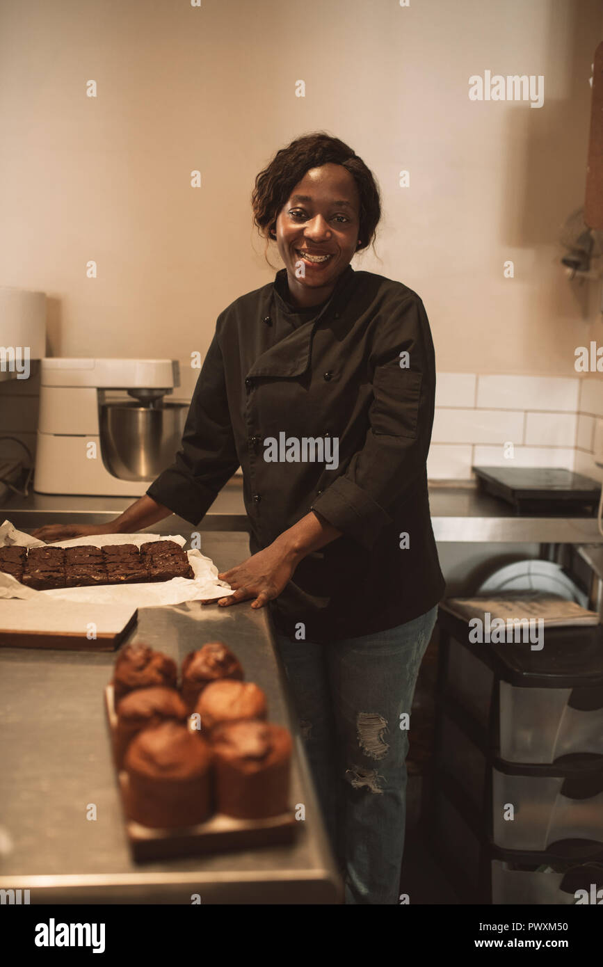 Smiling baker travaillant au comptoir d'une cuisine commerciale Banque D'Images