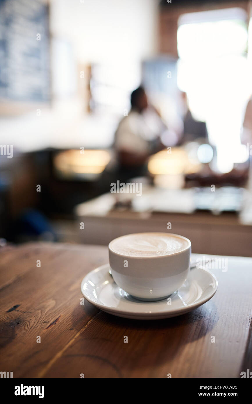 Café Cappuccino sur une table avec des clients à l'arrière-plan Banque D'Images