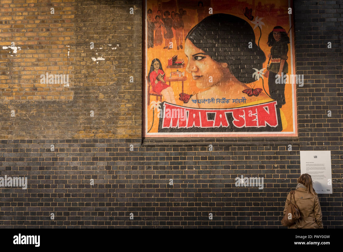 Londres, Royaume-Uni. 18 octobre 2018. Un passant par des vues d'une nouvelle illustration de Justine Sehra dans Brick Lane. Caractéristiques de l'oeuvre de l'activiste des droits de l'Eze Sen et est l'un des 20 œuvres commandées récemment connu sous le nom d'annuaire local WMN, conçu par l'ensemble de l'équipe de la Tate de Londres, Tate's group de 16 à 25 ans, les artistes qui s'affiche dans l'espace public à travers la ville marquant le centenaire du vote des femmes. Crédit : Stephen Chung / Alamy Live News Banque D'Images