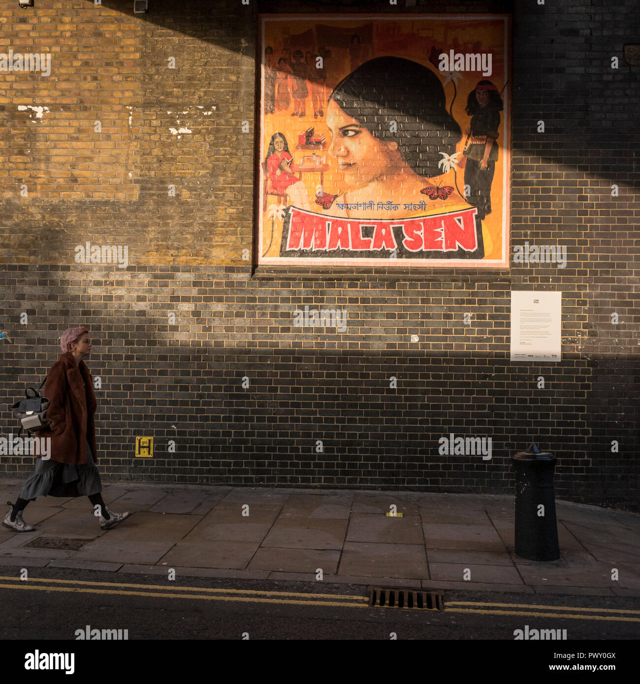 Londres, Royaume-Uni. 18 octobre 2018. Une femme marche par une nouvelle illustration de Justine Sehra dans Brick Lane. Caractéristiques de l'oeuvre de l'activiste des droits de l'Eze Sen et est l'un des 20 œuvres commandées récemment connu sous le nom d'annuaire local WMN, conçu par l'ensemble de l'équipe de la Tate de Londres, Tate's group de 16 à 25 ans, les artistes qui s'affiche dans l'espace public à travers la ville marquant le centenaire du vote des femmes. Crédit : Stephen Chung / Alamy Live News Banque D'Images