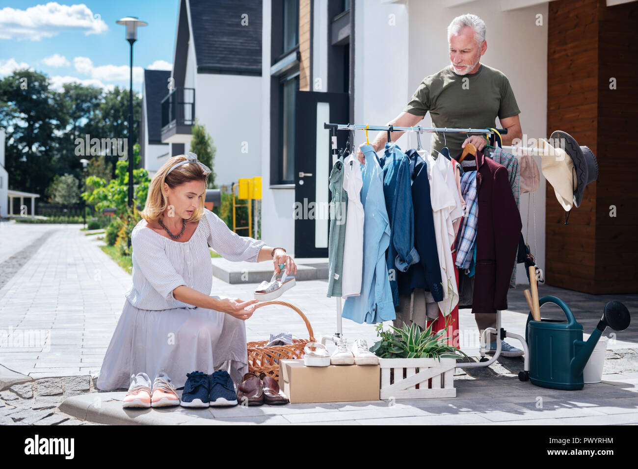 Appel blonde-haired woman wearing robe rayée à la vente de bric-à chaussures à Banque D'Images