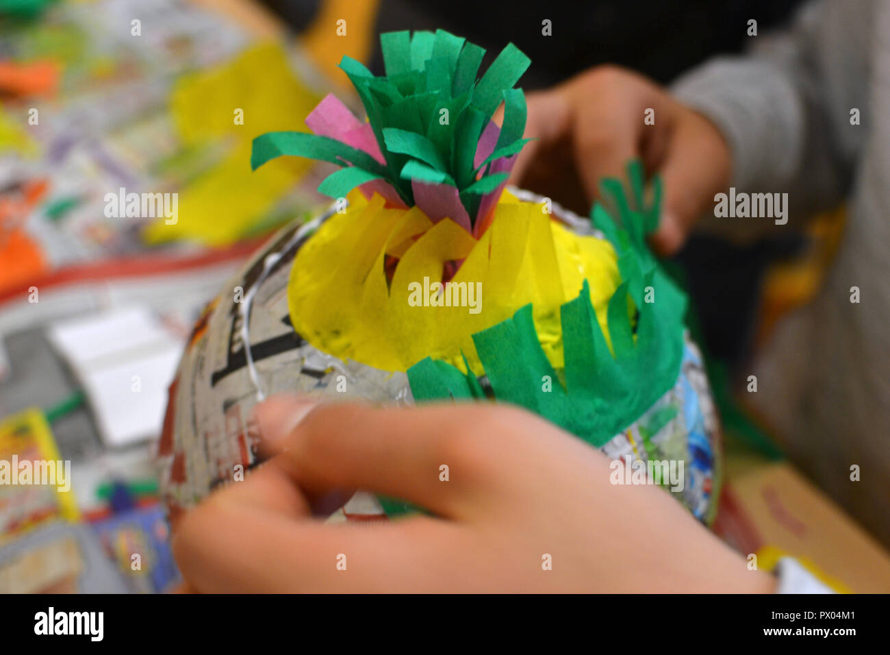 Les mains des enfants font une pinata coloré avec du papier et de la colle. Banque D'Images