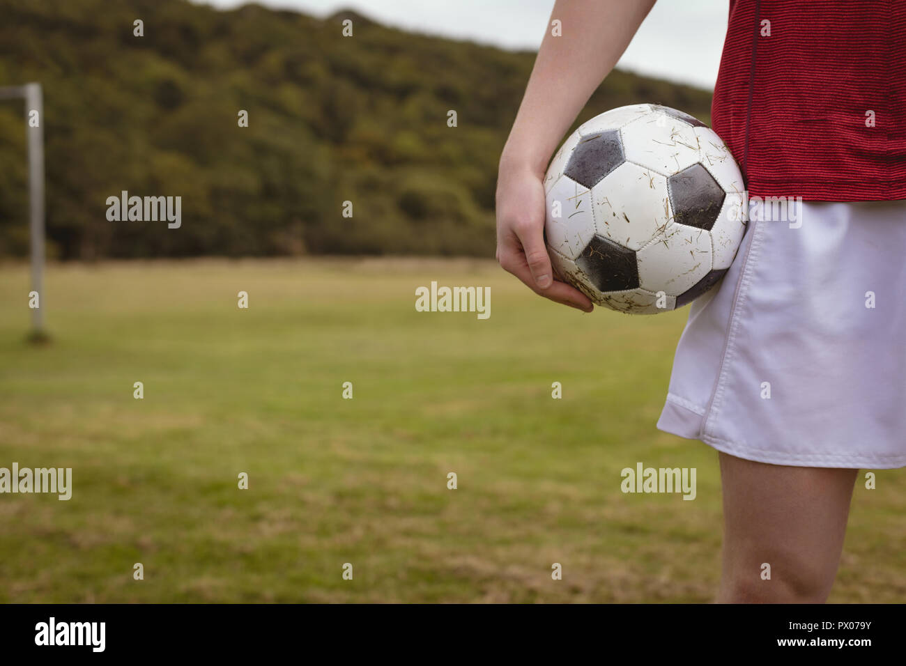 Joueur de football debout avec ballon de soccer dans le domaine Banque D'Images