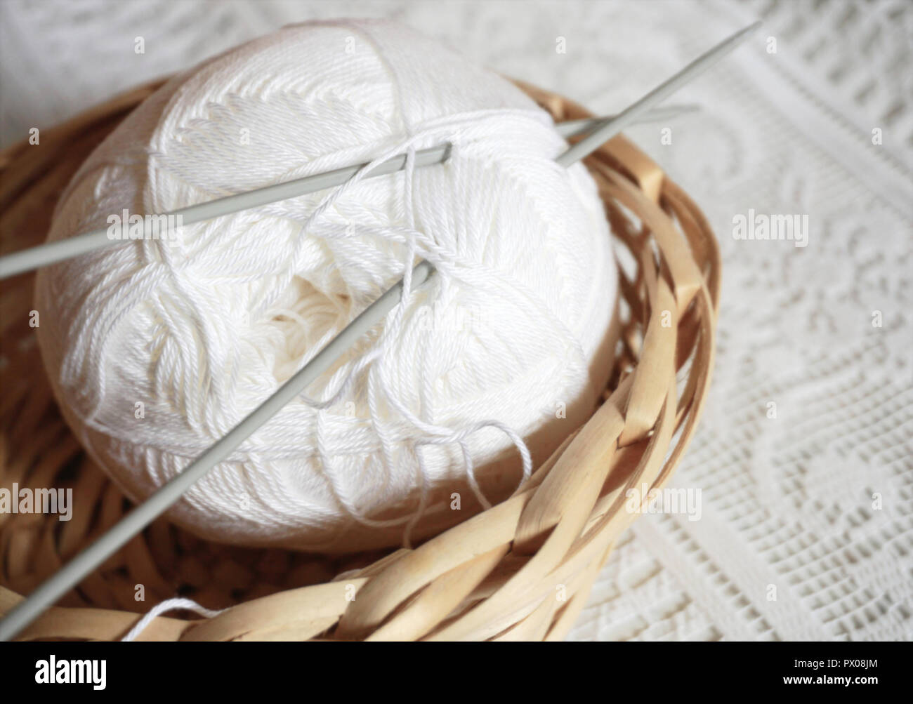 Balle de laine à tricoter dans le vintage panier en osier sur le fond de dentelle. L'activité d'accueil confortable concept. Banque D'Images