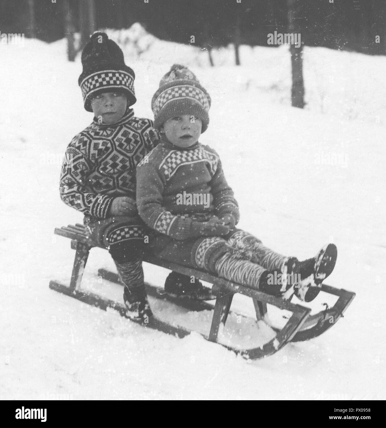 L'hiver au début du xxe siècle. Prince, Gustaf Adolf 1906-1947 et son jeune frère Bertil est à l'extérieur de jouer dans la neige. Ils sont assis sur une luge correctement vêtus de vêtements en tricot chaud, chandails, gants et chapeau. La Suède ca 1910 Banque D'Images