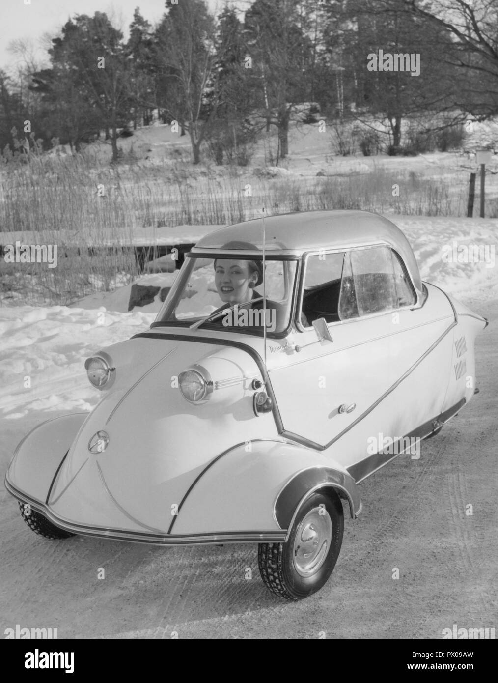 La conduite en hiver dans les années 1950. Une jeune femme est le moteur de la berline allemande Messerschmitt KE200. Une petite voiture à trois roues avec suffisamment de place pour mettre en place deux adultes et un enfant dans la voiture. La voiture a été fabriquée entre 1955-1964. Suède 1955 Banque D'Images