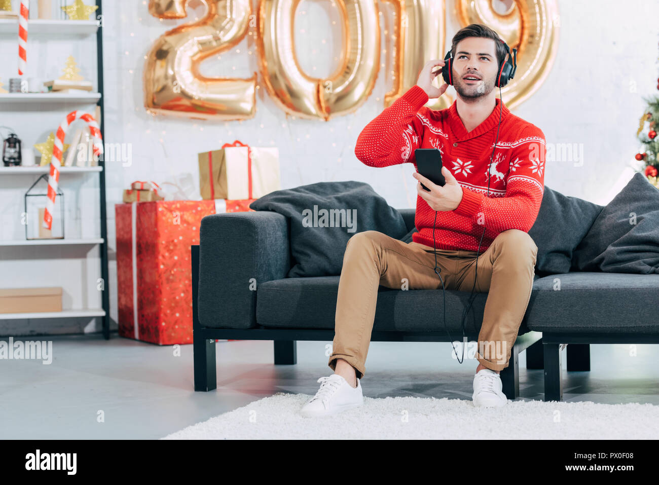 Jeune homme à l'écoute de la musique avec des écouteurs et du smartphone sur le nouvel an 2019 Banque D'Images