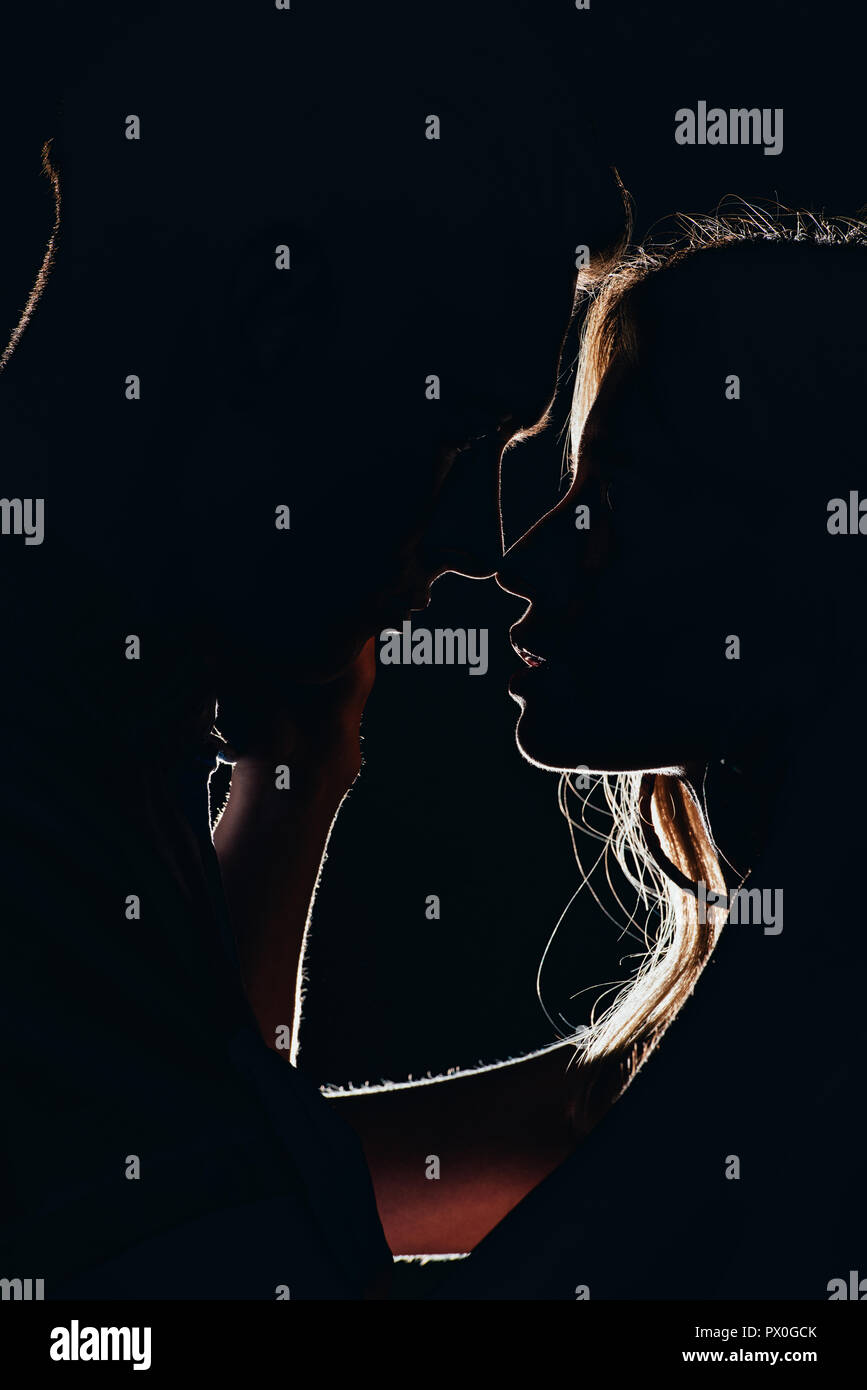 Silhouettes d'offres jeune couple va baiser dans le noir Banque D'Images