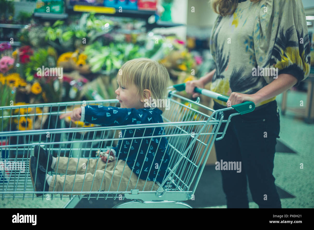 Un petit enfant est assis dans un caddie dans un supermarché Banque D'Images