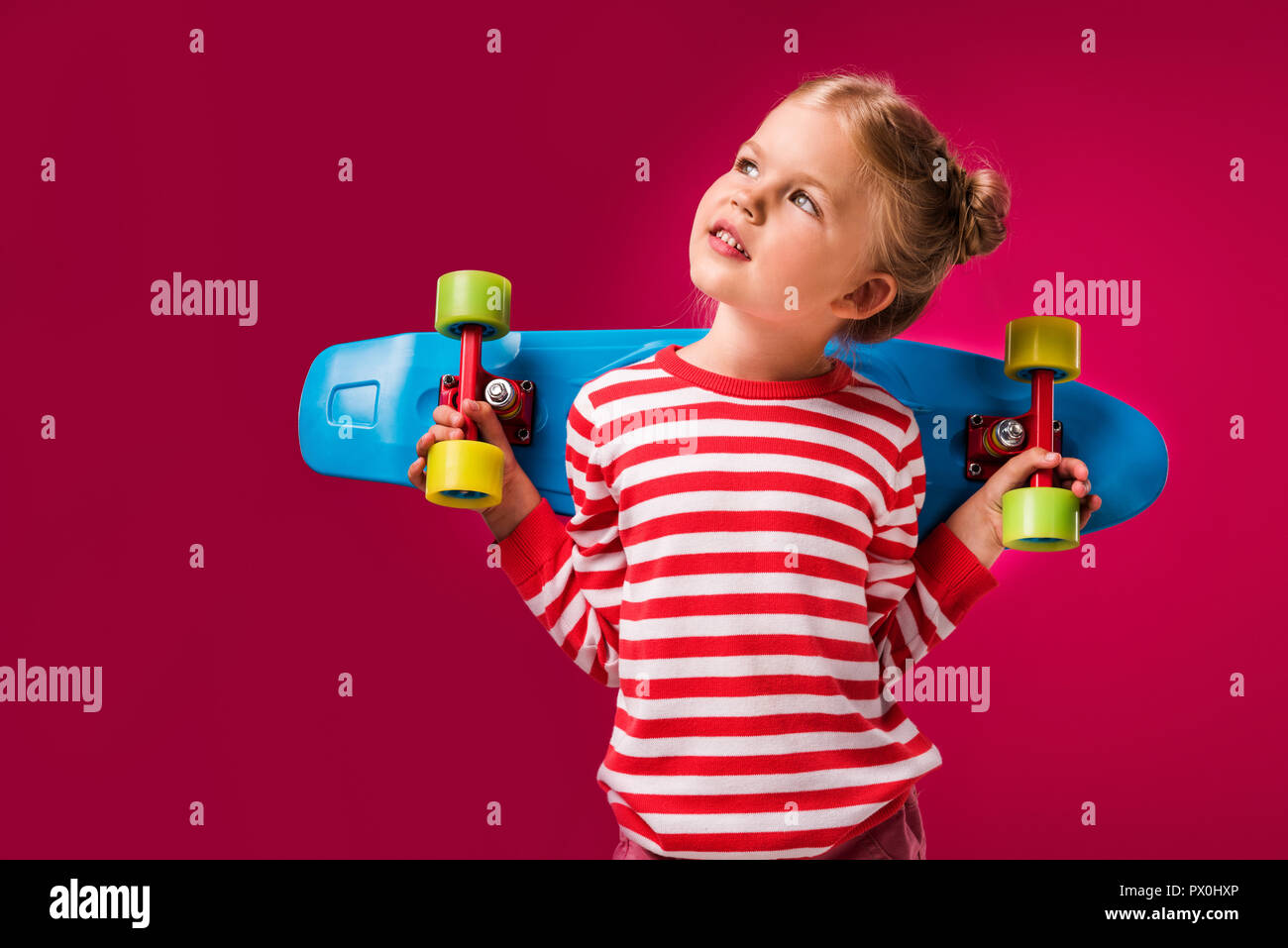 Adorable enfant élégants posant avec penny rouge isolé sur conseil Banque D'Images