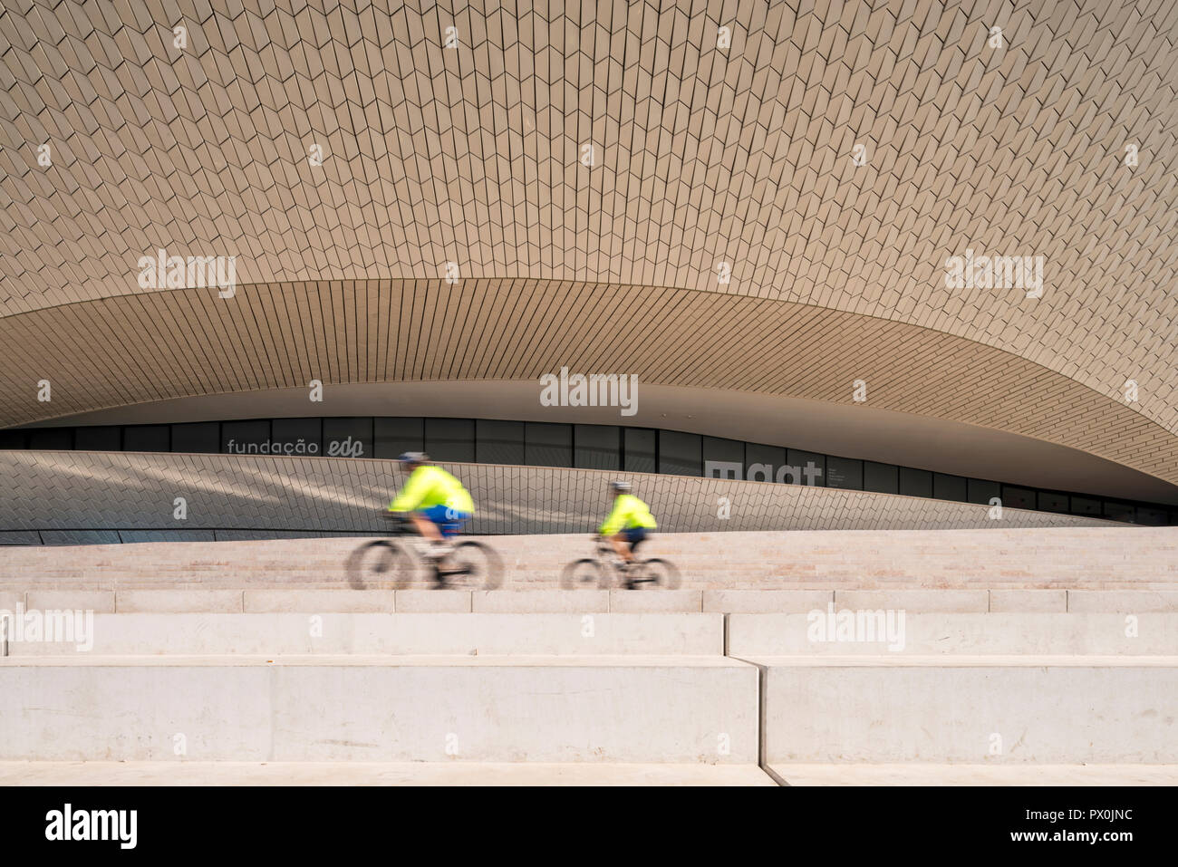 Vue extérieure de la MAAT - Musée d'art, d'architecture et de la Technologie, Lisbonne, Portugal. Deux cyclistes sur les étapes d'une terrasse. Banque D'Images