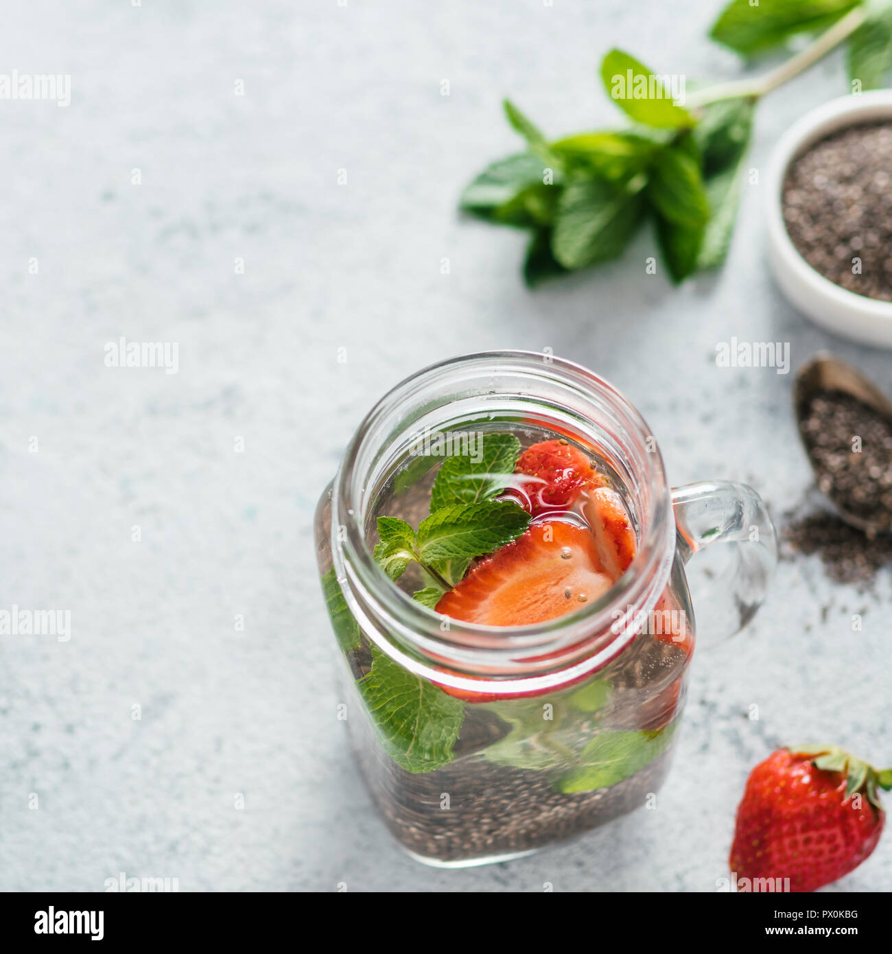 Vue du dessus de l'eau dans la région de chia pot Mason avec fraise et menthe sur fond de ciment gris. Chia infusé avec de l'eau detox de baies. L'espace de copie pour le texte. La saine alimentation, boissons, alimentation, concept detox Banque D'Images