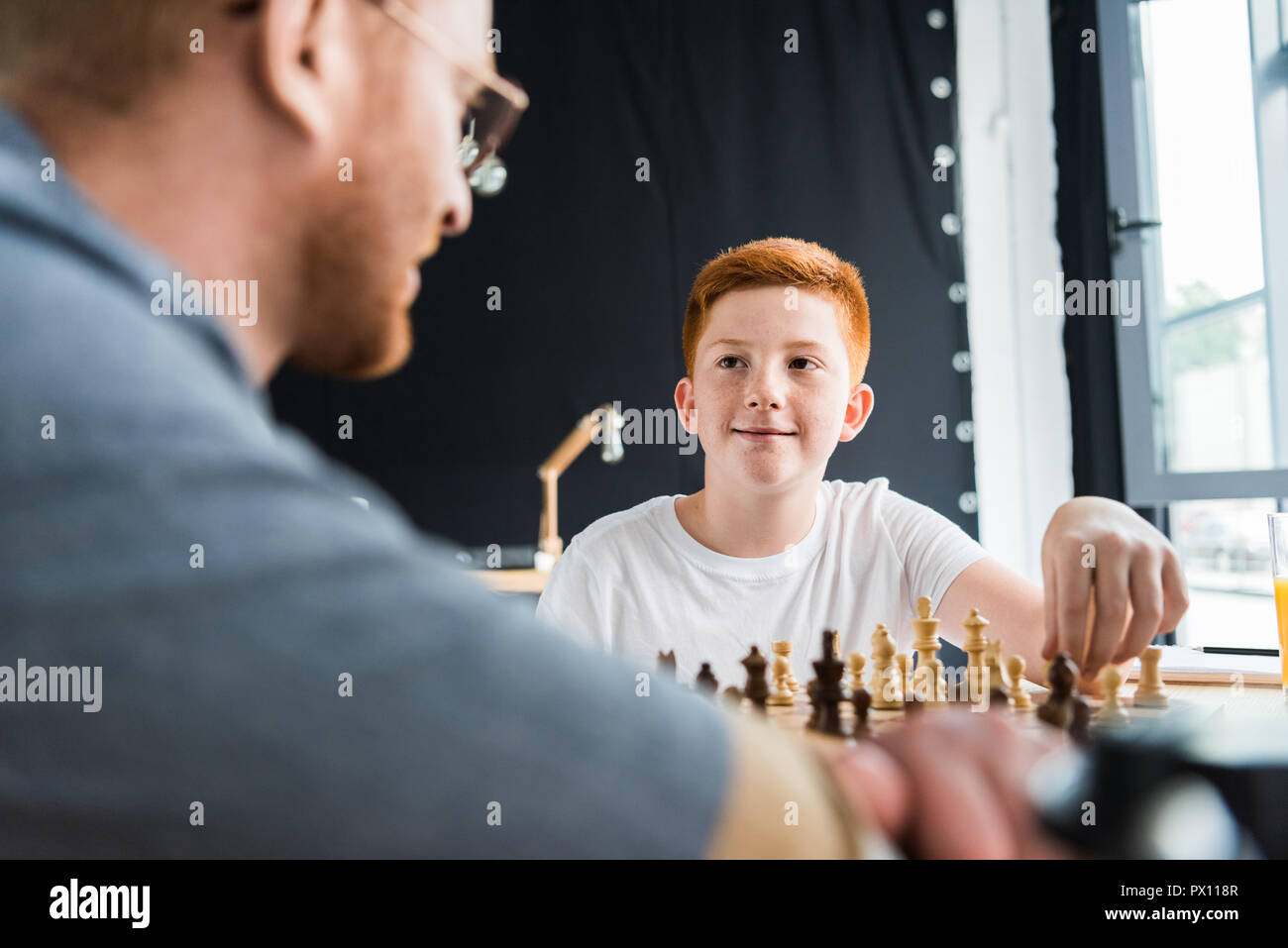 Père et fils en jouant aux échecs et à la recherche à l'autre à la maison Banque D'Images