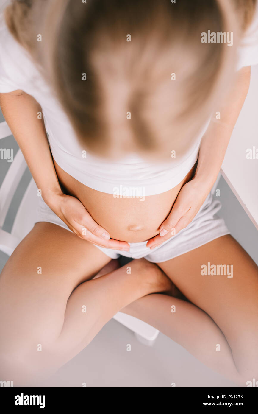 Vue de dessus de femme enceinte avec les mains sur le ventre à la maison Banque D'Images