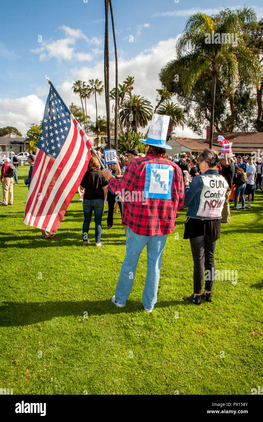 Portant un drapeau américain, les défenseurs du contrôle des armes à feu démontrer dans un Long Beach, CA, parc municipal. Remarque hat avec signe. Banque D'Images