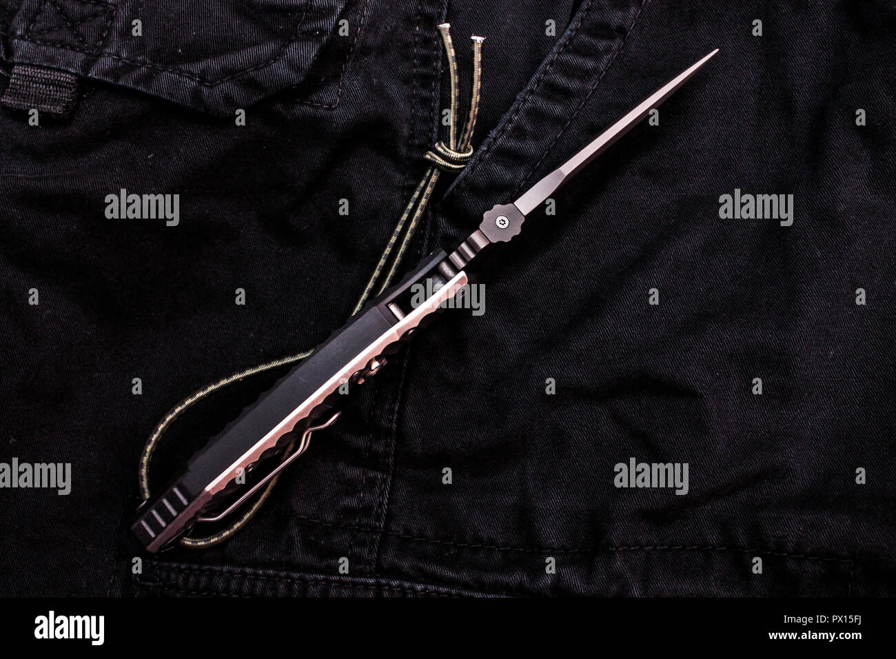 - Coup de couteau militaire. Vue de dessus du couteau. Pantalon militaire noir. Banque D'Images