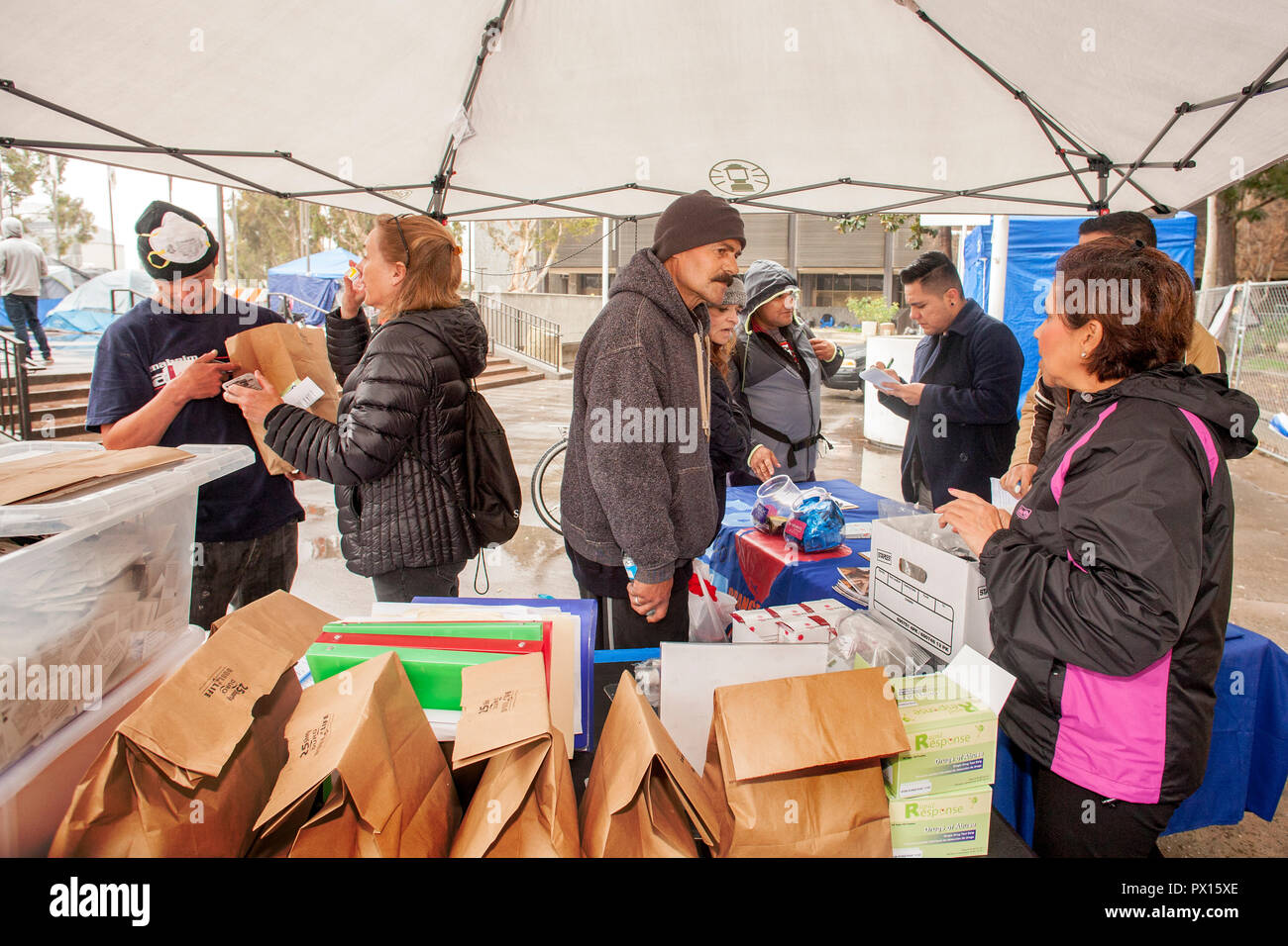 Pour lutter contre l'overdose aux opiacés, multiracial volontaires distribuent des kits d'antidote de Naloxone dans des sacs en papier à un campement de sans-abri à Santa Ana, CA. Banque D'Images