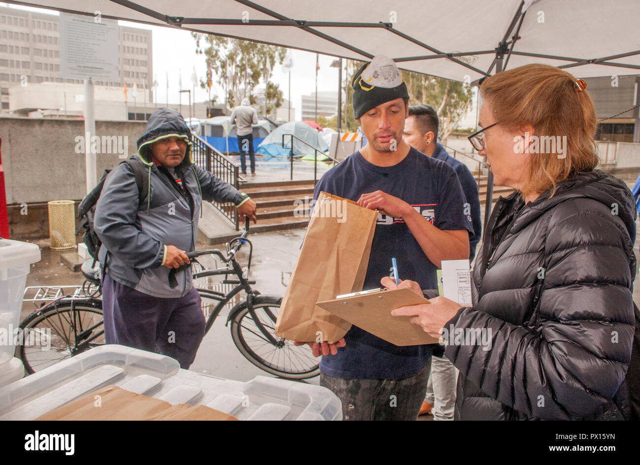 Pour lutter contre l'overdose aux opiacés, multiracial volontaires distribuent des kits d'antidote de Naloxone dans des sacs en papier à un campement de sans-abri à Santa Ana, CA. Remarque tentes en arrière-plan. Banque D'Images
