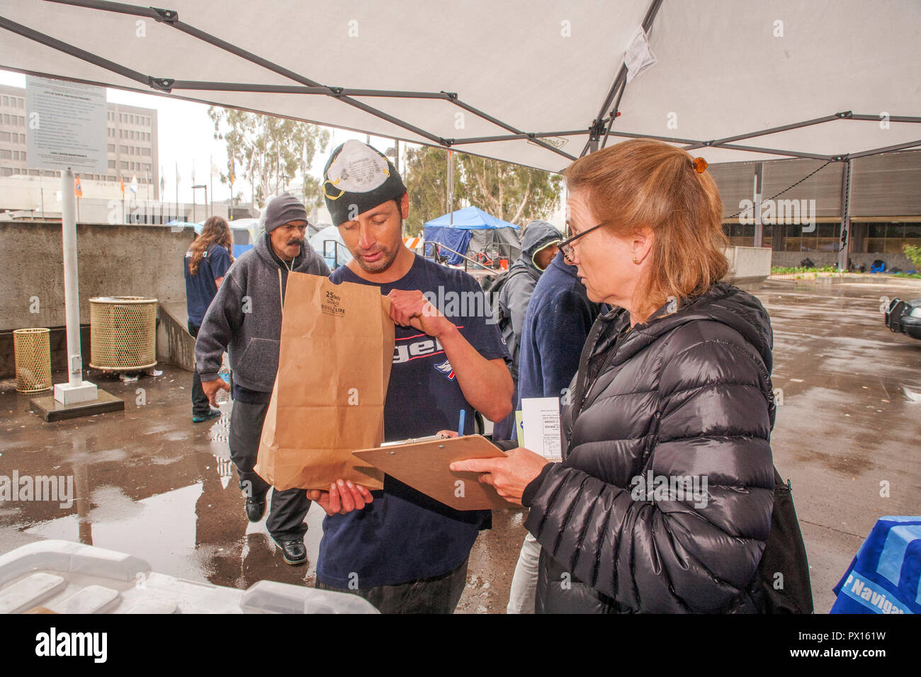 Pour lutter contre l'overdose aux opiacés, multiracial volontaires distribuent des kits d'antidote de Naloxone dans des sacs en papier à un campement de sans-abri à Santa Ana, CA. Banque D'Images