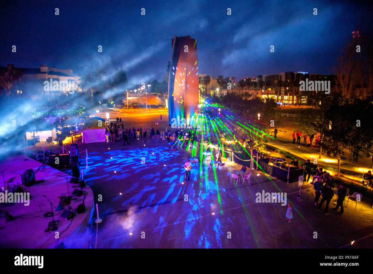 Les rayons laser qui brillent à travers la fumée à un festival en plein air de la communauté à Costa Mesa, CA. Dans le centre est la sculpture de Richard Serra 'Connecteur.' Banque D'Images
