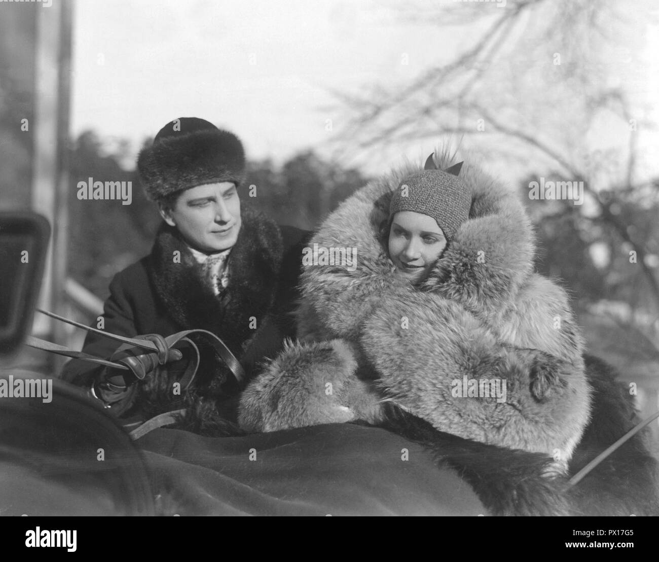 Manteau de fourrure dans les années 1930. Un jeune couple est assis ensemble dans une carriole. La femme porte un manteau de fourrure. Photo du tournage du film Charlotte Löwensköld 1930. Banque D'Images