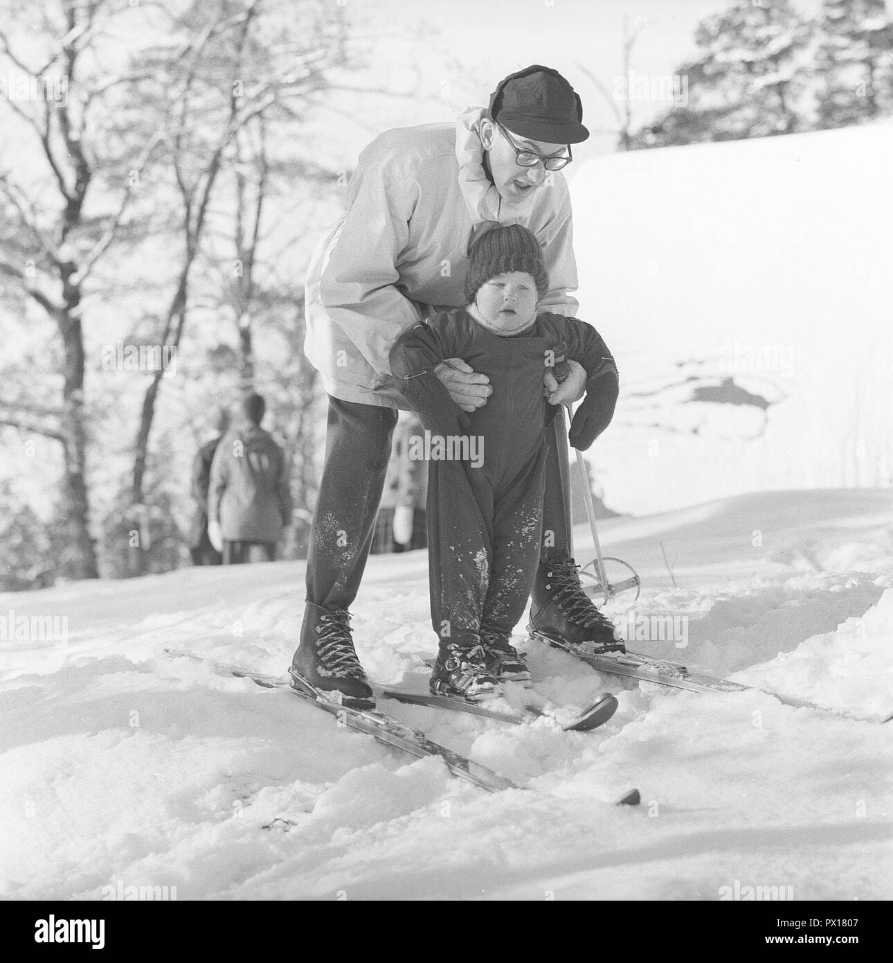 L'hiver dans les années 1960. Un père et son fils sont en train de vivre une journée d'hiver le ski. Le garçon reçoit de l'aide de l'équilibre lui-même sur les skis. C'est un jour d'hiver à Fiskartorpet à Stockholm Février 1960. Banque D'Images