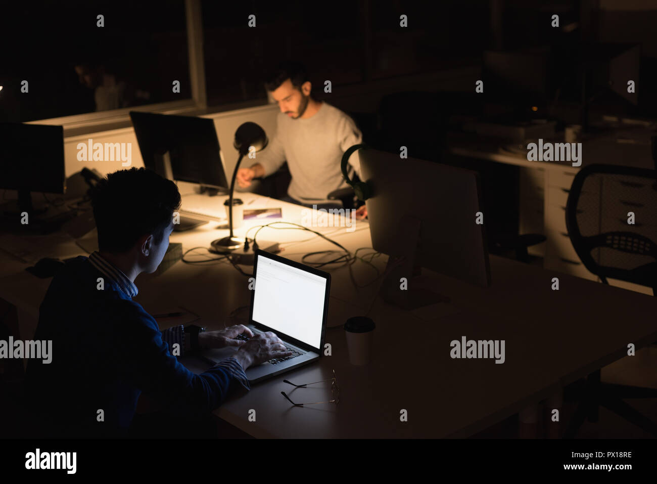 Hommes d'working on laptop in office pendant la nuit Banque D'Images