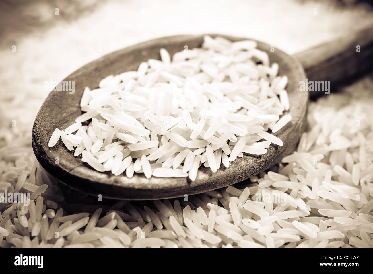Une cuillère de cuisine en bois sur un tas de riz, des couleurs monochromes Banque D'Images