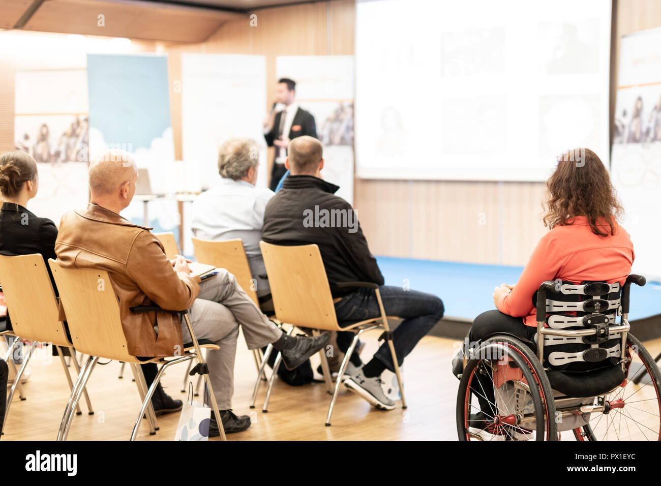 Vue arrière du nrecognizable femme sur un fauteuil roulant qui participent à des discours de conférence. Banque D'Images