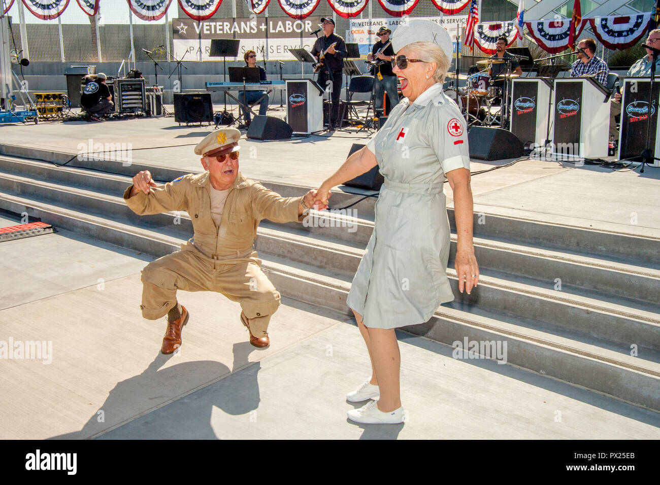 Un ancien combattant de la Seconde Guerre mondiale en uniforme de l'Armée US et d'une femme vêtue comme une volontaire de la Croix Rouge l'jutterbug danse joyeusement à une célébration de la Journée des anciens combattants à Costa Mesa, CA. Banque D'Images