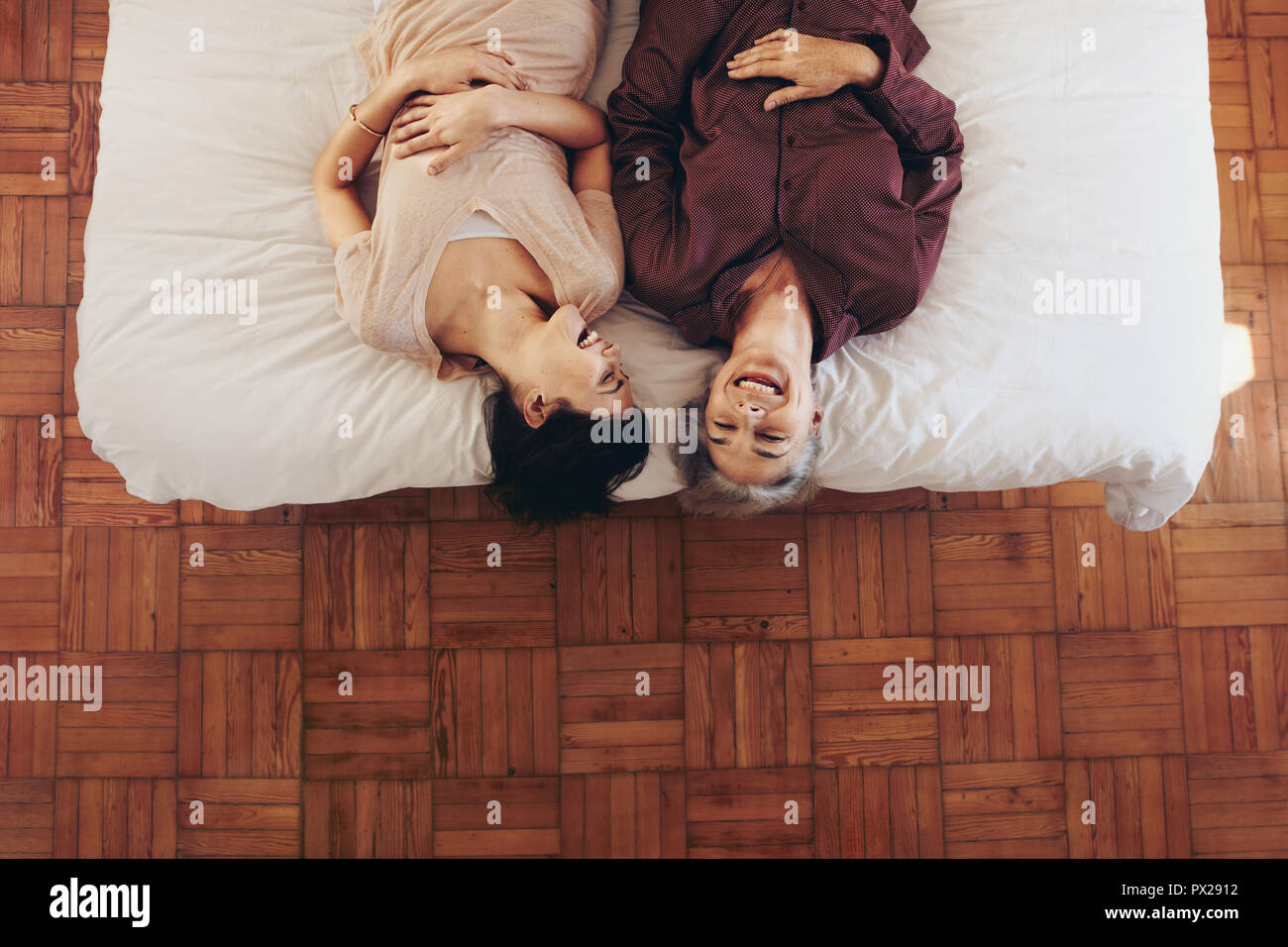 Mother and Daughter lying on bed et rire. Femme passant du temps à parler avec sa mère âgée lying on bed at home. Banque D'Images