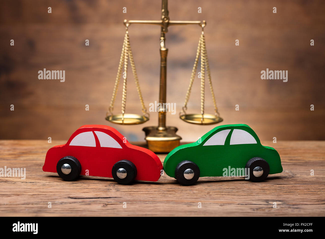 Close-up of two Voiture rouge et vert en face de la Justice sur l'échelle d'un bureau en bois Banque D'Images