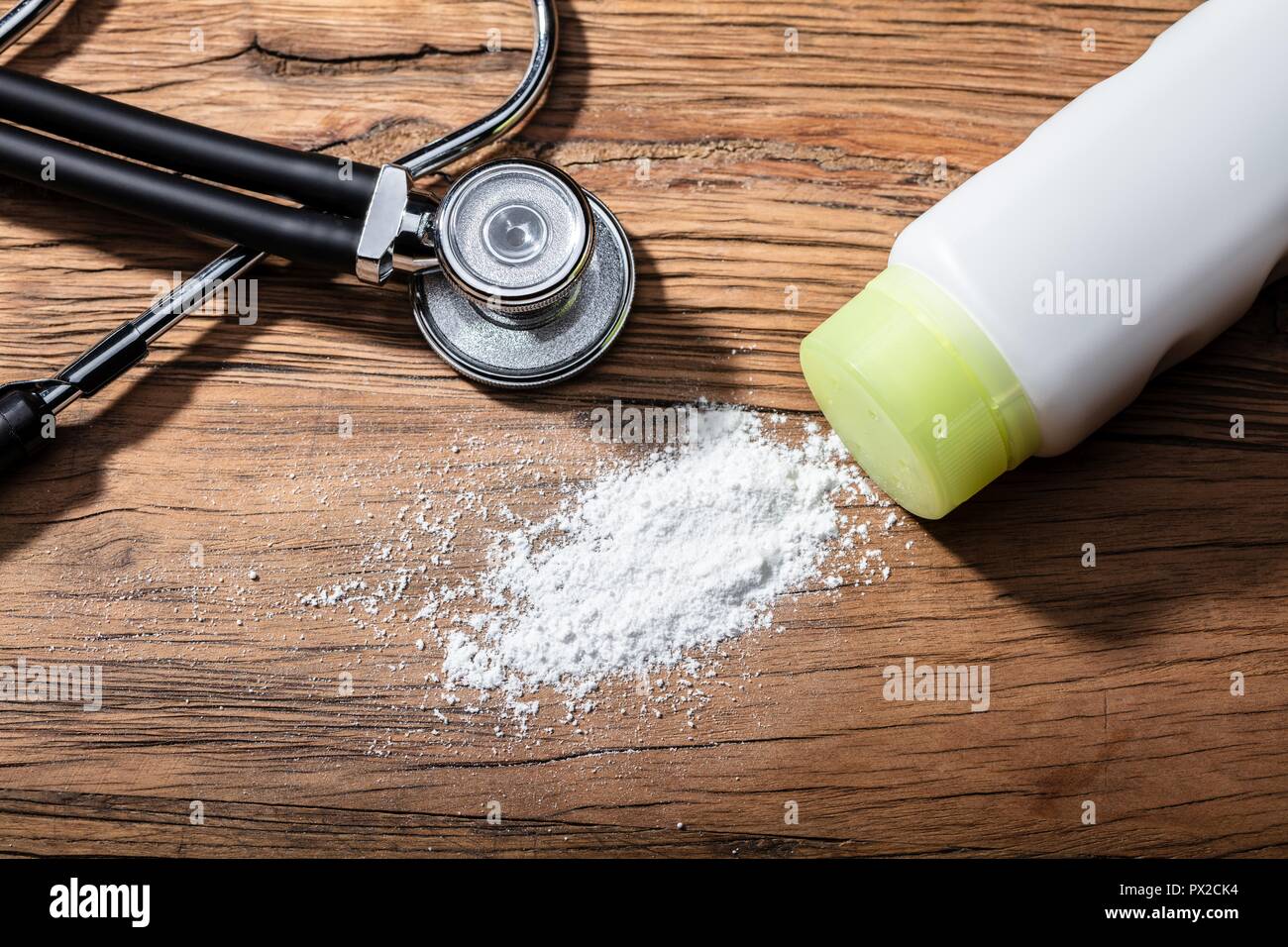 Close-up du produit répandu de la poudre de talc et stéthoscope sur fond de bois Banque D'Images