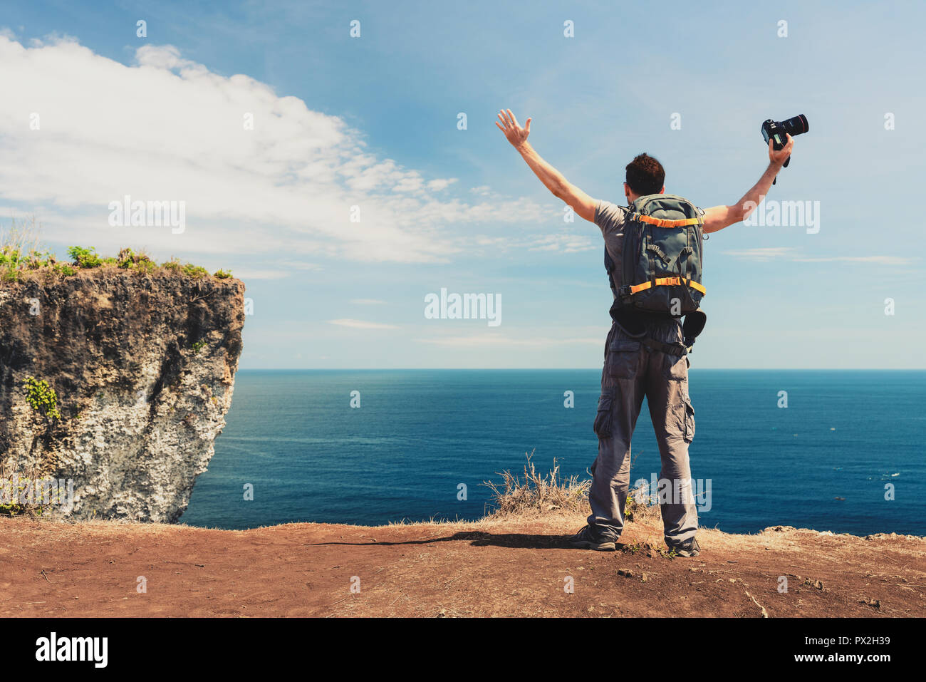 Succès et Travel concept. Heureux backpacker avec caméra à la main debout sur une falaise de montagne et profiter d'une excellente nature paysage Banque D'Images