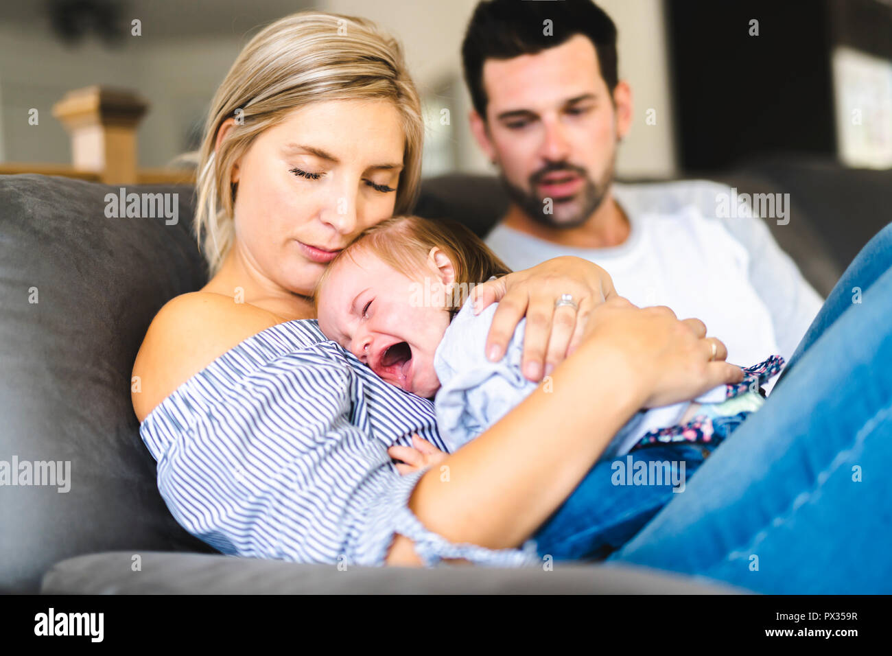 Jeune Famille Avec Bebe Fille Le Canape A La Maison Le Bebe Qui Pleure Photo Stock Alamy