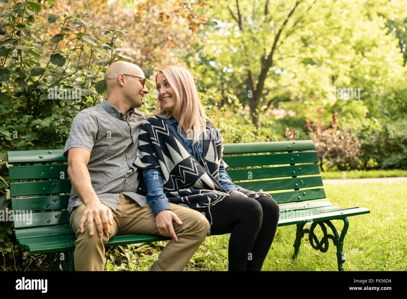 Un jeune couple assis sur un banc au parc. Banque D'Images