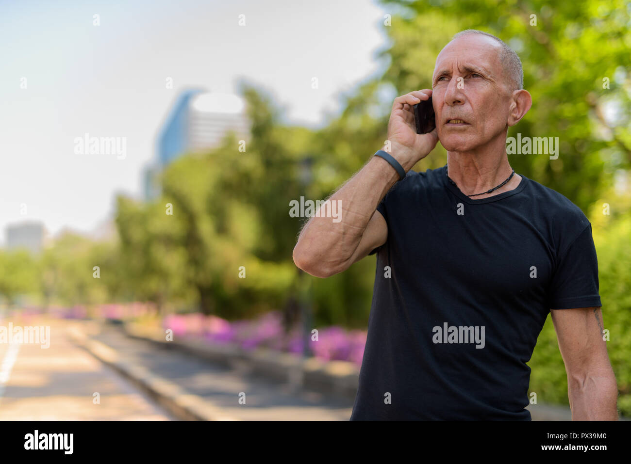 Senior homme chauve touristique pensée tout en parlant sur un téléphone mobile Banque D'Images