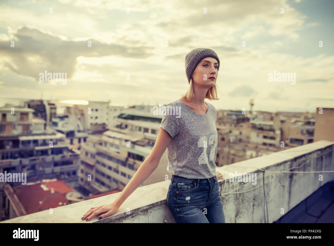 Jeune femme se poser sur un toit de la rue portant des vêtements de style urbain Banque D'Images