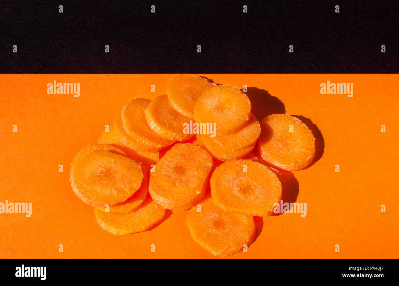 Un beau bouquet de carottes coupées sur un arrière-plan coloré ,Vue de dessus ,studio shot , l'harmonie de couleur orange et noir Banque D'Images