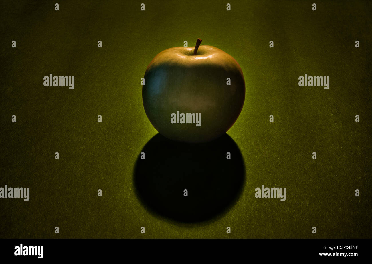 Une pomme verte sur un fond vert et noir , studio shot ,un contraste élevé , vue de face , le fruit est une rétro-éclairé , apple sombre ombre sur la foreg Banque D'Images