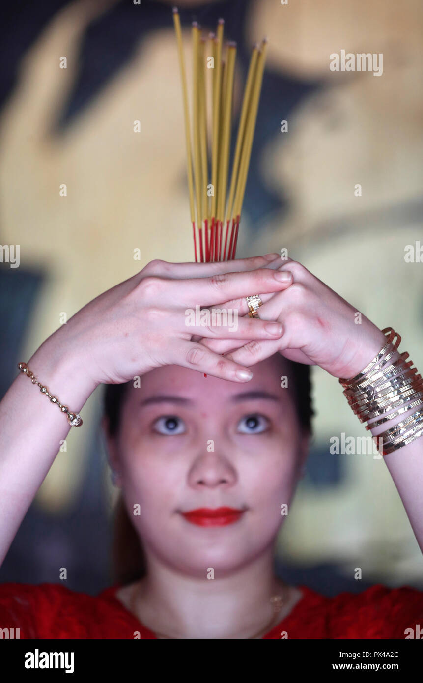 L'Empereur de Jade. Vietnamienne en rouge robe longue traditionnelle Ao Dai en priant avec d'encens. Ho Chi Minh Ville. Le Vietnam. Banque D'Images