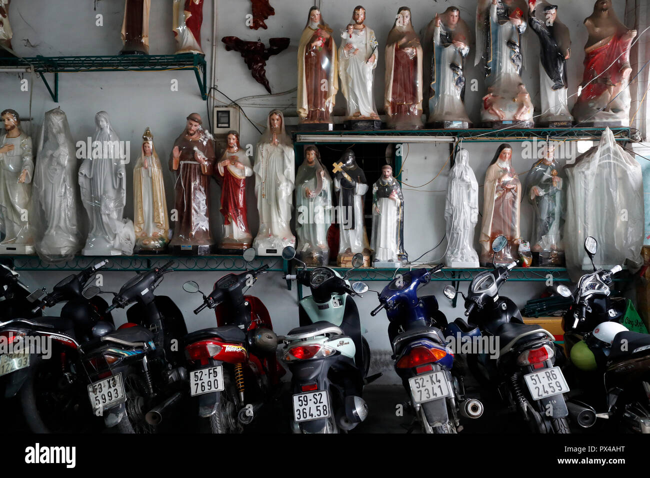 Magasin de vente d'articles religieux chrétiens. Jésus Sainte Vierge statues parmi les motos. Ho Chi Minh Ville. Le Vietnam. Banque D'Images