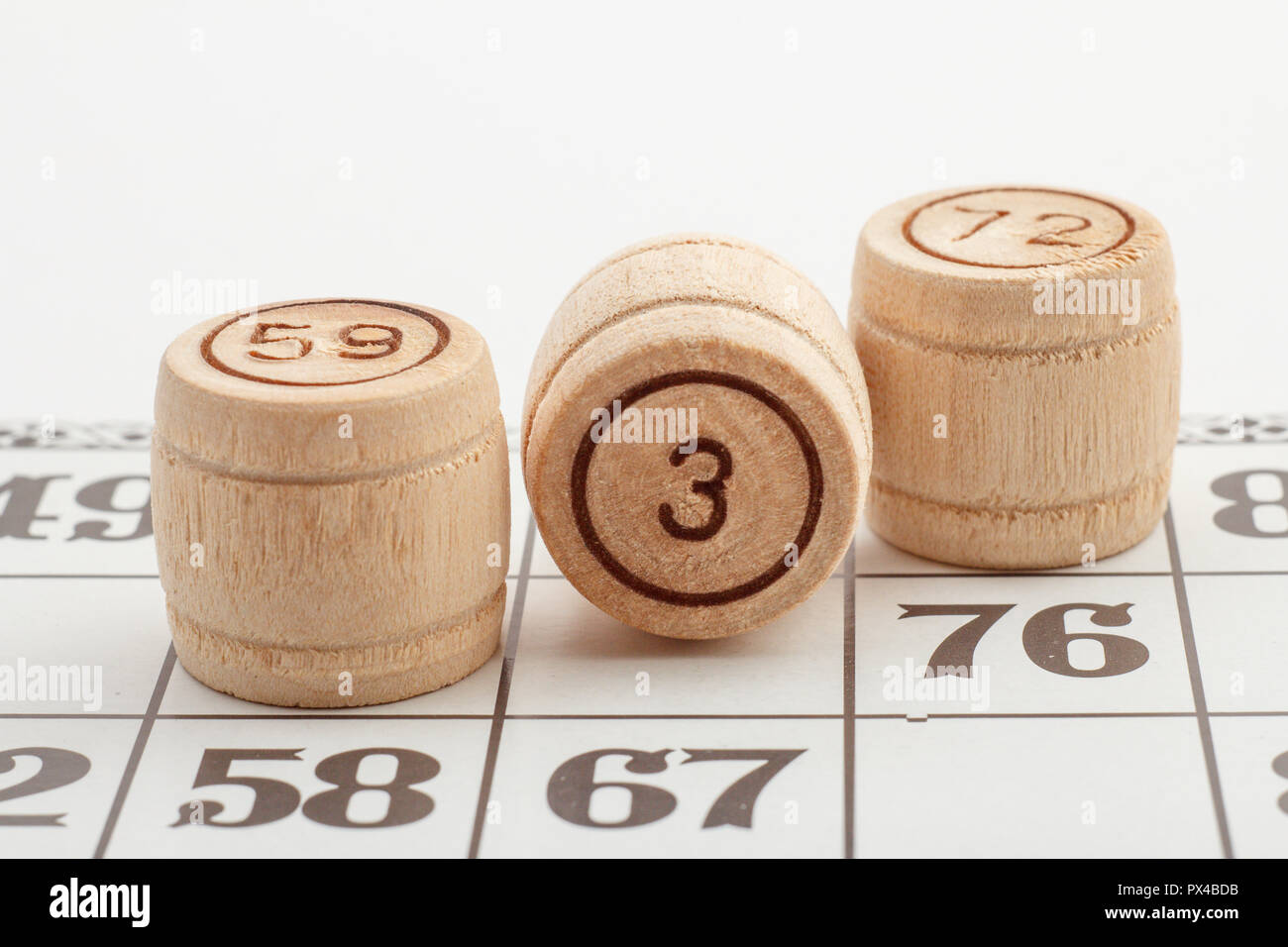 Tonneau en bois et trois numéros de carte pour un jeu de loto sur un fond blanc. Vue rapprochée Banque D'Images