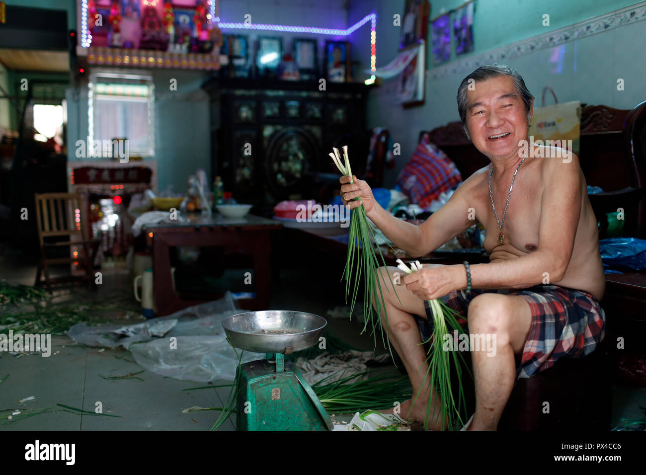 Homme prpearing oignons de printemps dans sa maison. Ho Chi Minh Ville. Le Vietnam. Banque D'Images